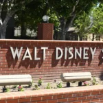 Brick wall with "the walt disney studios" sign, surrounded by greenery and light fixtures