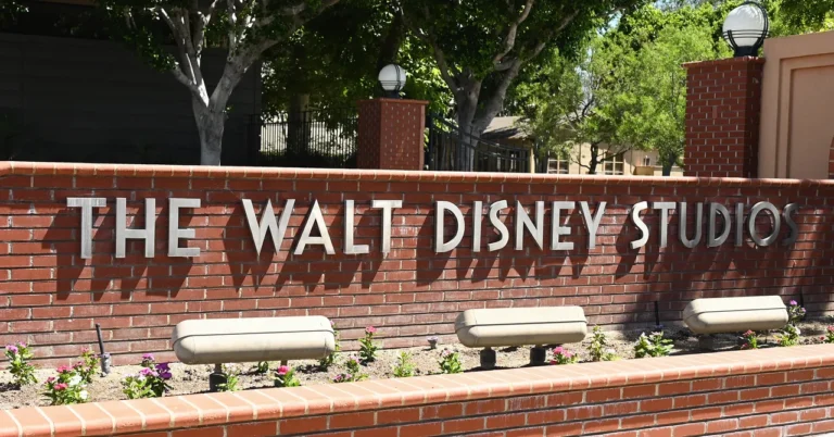 Brick wall with "the walt disney studios" sign, surrounded by greenery and light fixtures