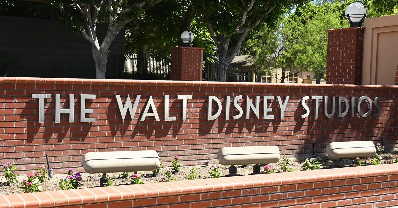 Brick wall with "the walt disney studios" sign, surrounded by greenery and light fixtures