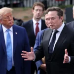 Group of men in suits conversing outdoors, one gesturing while others listen attentively, no visible text.