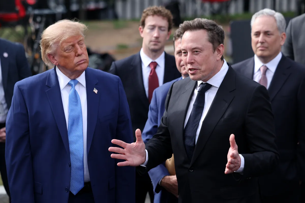 Group of men in suits conversing outdoors, one gesturing while others listen attentively, no visible text.