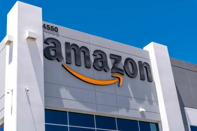 Amazon logo on a gray building facade with address number 4550 against a clear blue sky.