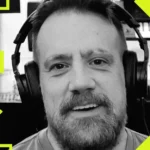 Man wearing headphones, smiling, with abstract yellow geometric shapes and blurred equipment in the background.