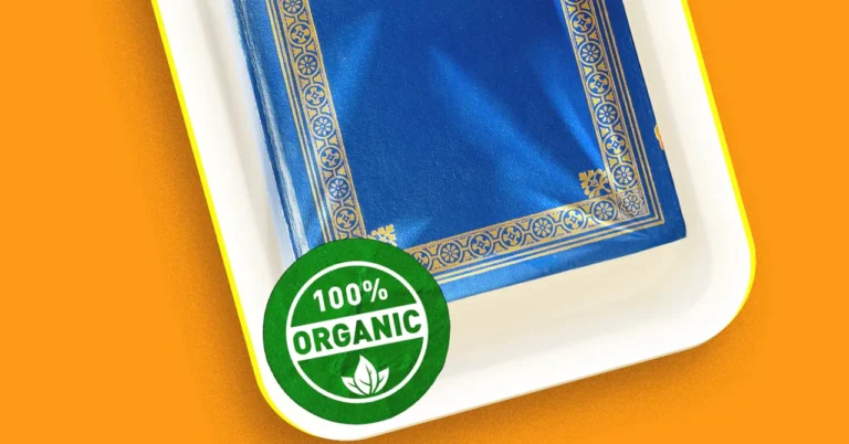 Blue book with gold decorative border on a white tray, green "100% Organic" seal in the corner, orange background.