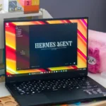 Laptop displaying "Hermes Agent" software on screen, surrounded by toy blocks and educational items on a desk.