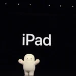 Cute white figure stands on stage with "iPad" displayed on a large screen above, surrounded by small lights