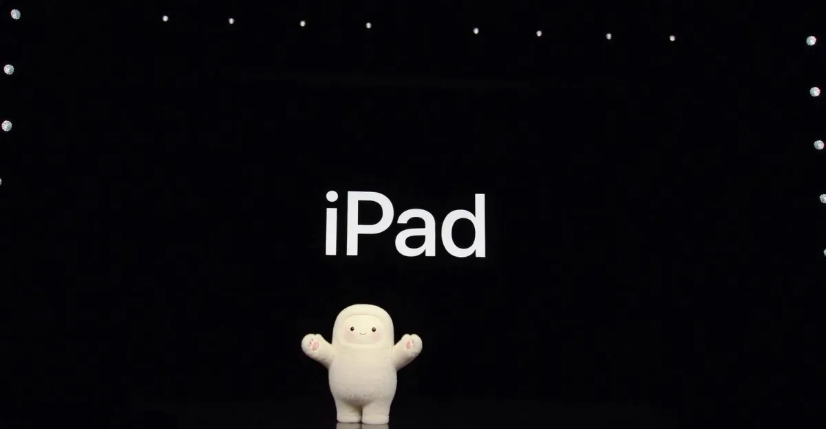 Cute white figure stands on stage with "iPad" displayed on a large screen above, surrounded by small lights