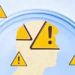 Silhouette of a human head surrounded by yellow warning signs with exclamation marks inside a blue circular frame.