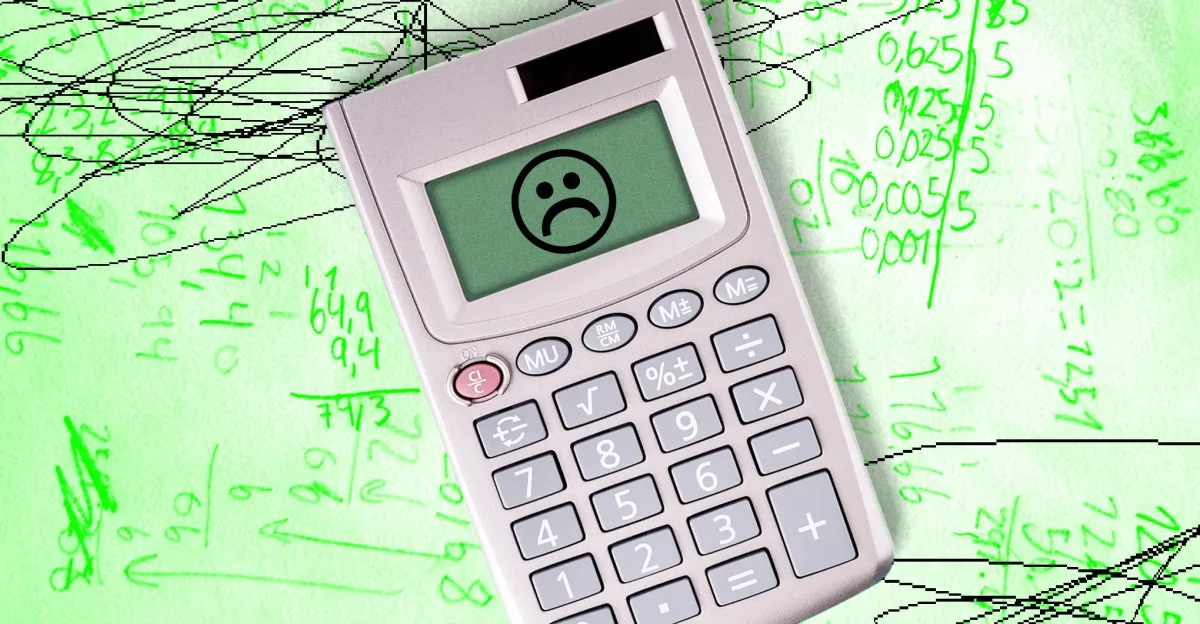 Calculator with a sad face on screen over green paper filled with handwritten mathematical equations and scribbles.