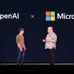 Two men on stage discussing under OpenAI and Microsoft logos on a dark background.