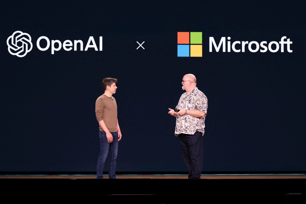 Two men on stage discussing under OpenAI and Microsoft logos on a dark background.