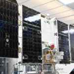 Satellite with solar panels in a laboratory setting, labeled "Planet. See Change. Change the World.