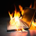 Laptop engulfed in flames on a dark background, symbolizing a cybersecurity threat or urgent tech issue.
