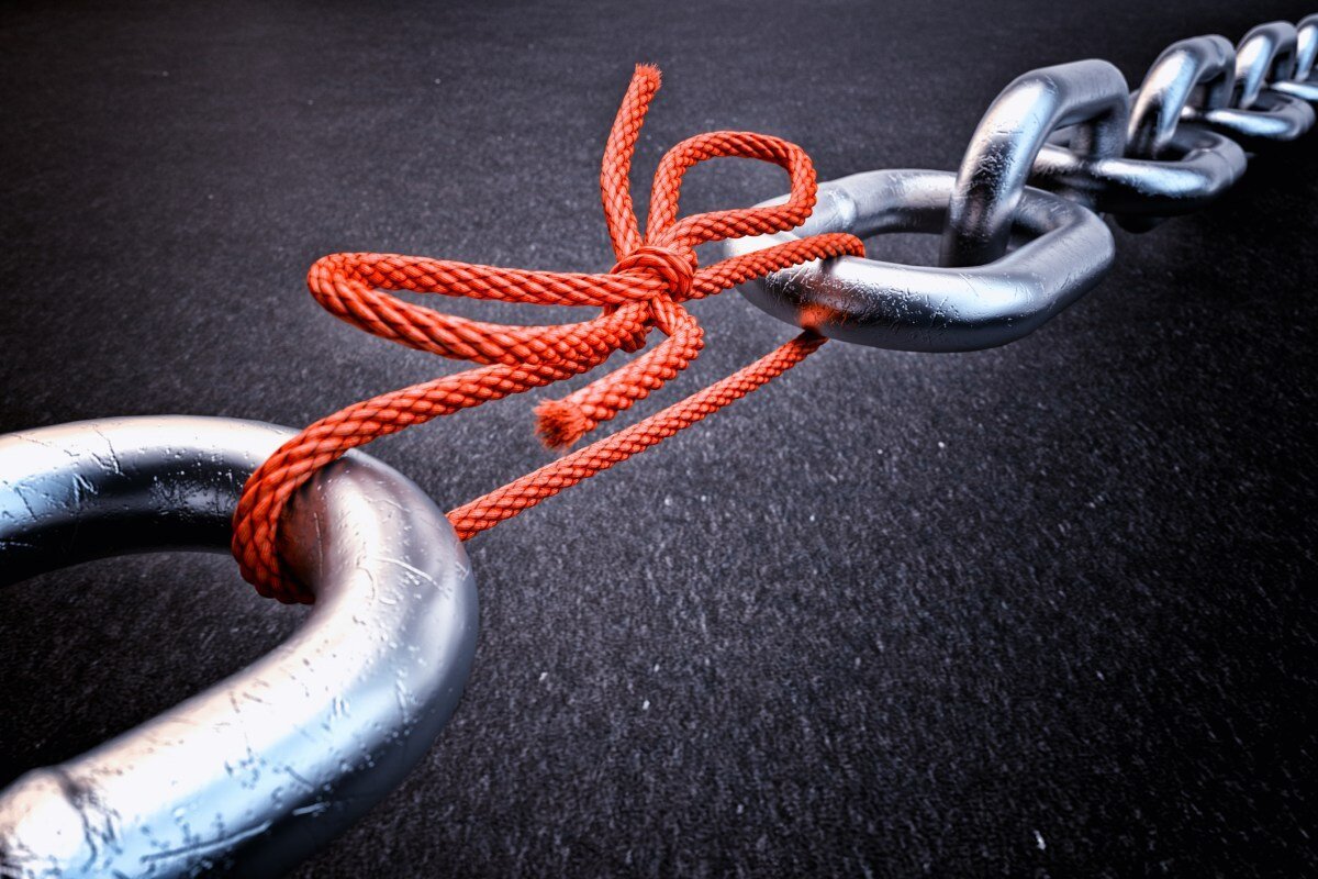 Metal chain link tied with a red rope against a dark background