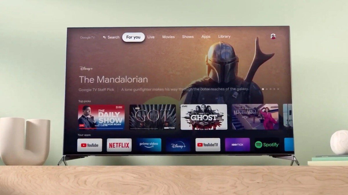 Smart TV interface displaying "The Mandalorian," with app icons for YouTube, Netflix, and more, on a wooden surface.