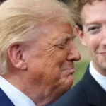 Two men in suits smiling outdoors, one with blonde hair in profile, the other with curly hair facing him.