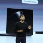 Person presenting on stage with Surface Laptop Ultra and RTX Spark Dev Box prices displayed; pre-order message above.